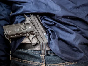 Handgun tucked in a person’s waistband on a bed, illustrating that actual physical possession of a gun may not be required for a firearm sentence enhancement