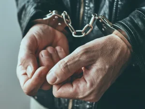 Close view of hands in metal handcuffs, symbolizing defendant facing victim injury points under Florida law