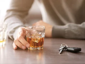 Man at table holding whiskey glass with car keys nearby showing impact of declining breath test during stop
