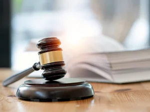 Judge’s gavel on a desk with a stack of legal documents in the background