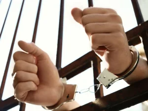 Hands in metal handcuffs gripping jail bars, symbolizing Florida criminal procedure from arrest to courtroom trial