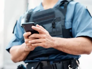 Uniformed officer using smartphone, symbolizing questions over police access to cell phones and online records