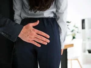 Male coworker touching female colleague inappropriately at work, illustrating workplace sexual harassment in Florida