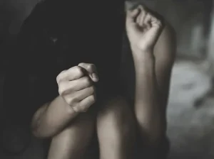 Terrified woman sitting on the floor with hands raised in self-defense, symbolizing sexual battery charges and lesser-included offenses in Florida criminal cases