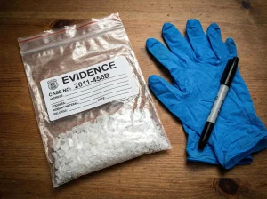 Evidence bag containing a crystalline substance on a wooden table next to blue gloves and a marker, representing admissibility of other-crimes evidence