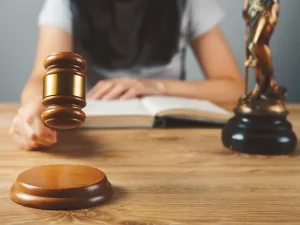 Judge with gavel beside law book and justice statue, symbolizing courts guarding defendants right to speedy trial