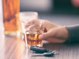 Hand holding whiskey glass beside car keys, symbolizing crucial evidence in Florida drunk driving fatality cases