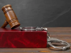 Wooden gavel on red law book beside handcuffs, symbolizing sentencing for releasee reoffender cases in Florida