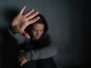 Terrified woman raising her hand to stop an attacker in a dark room
