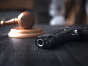 Close-up of a handgun on a table with a blurred judge’s gavel in the background, representing Miranda rights waiver issues