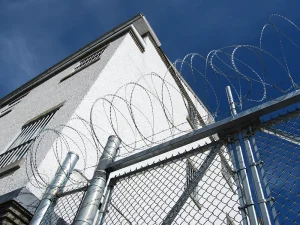 Prison building with razor wire fence and secure perimeter under a clear blue sky