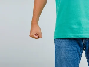 Person standing with a clenched fist, suggesting tension or conflict
