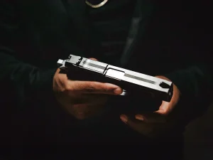 Man in dark clothing holding a handgun in low light, symbolizing a Florida gun crime case and sentencing issues