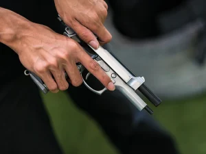 Close-up of a person racking the slide of a handgun, illustrating firearm possession issues in Florida violent career criminal cases